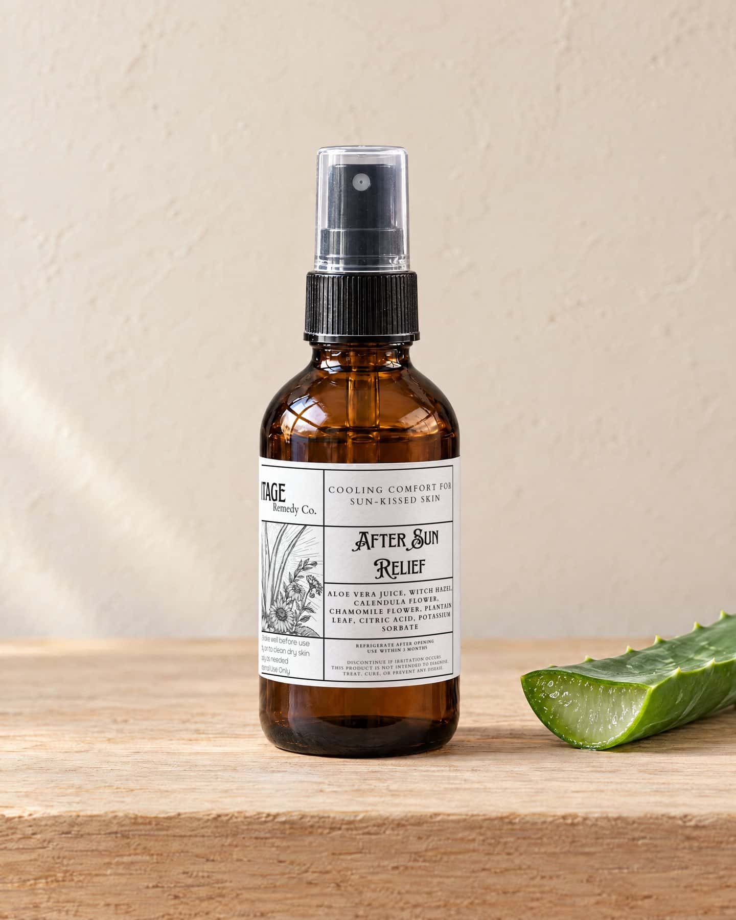 A spray bottle of After Sun Relief Spray on a pale oak shelf, a cut piece of fresh aloe vera leaf beside it