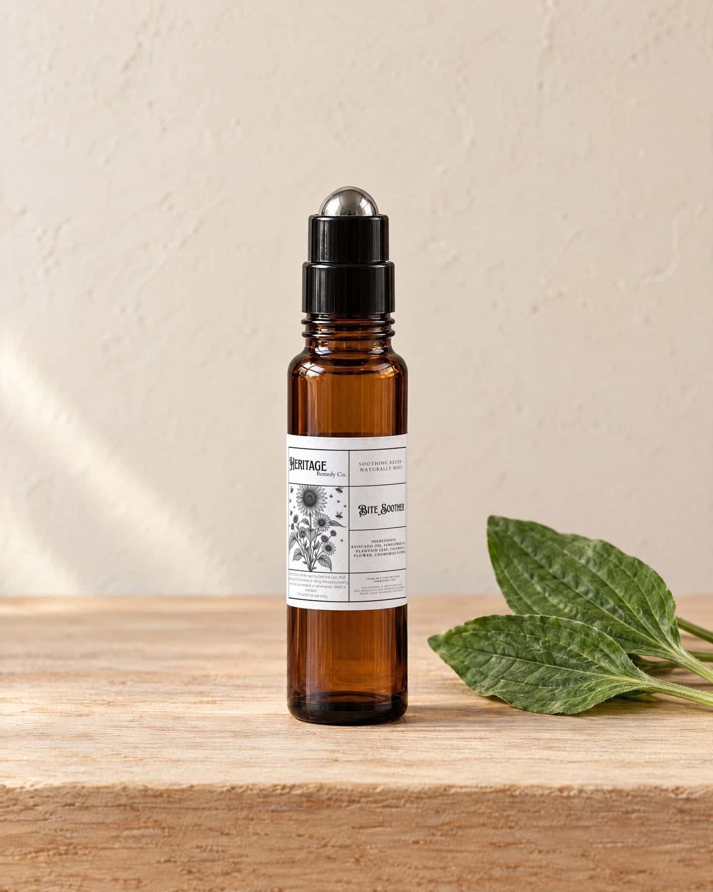 A roller bottle of Bite Soother Rollerball on a pale oak shelf, a few fresh broadleaf plantain leaves beside it