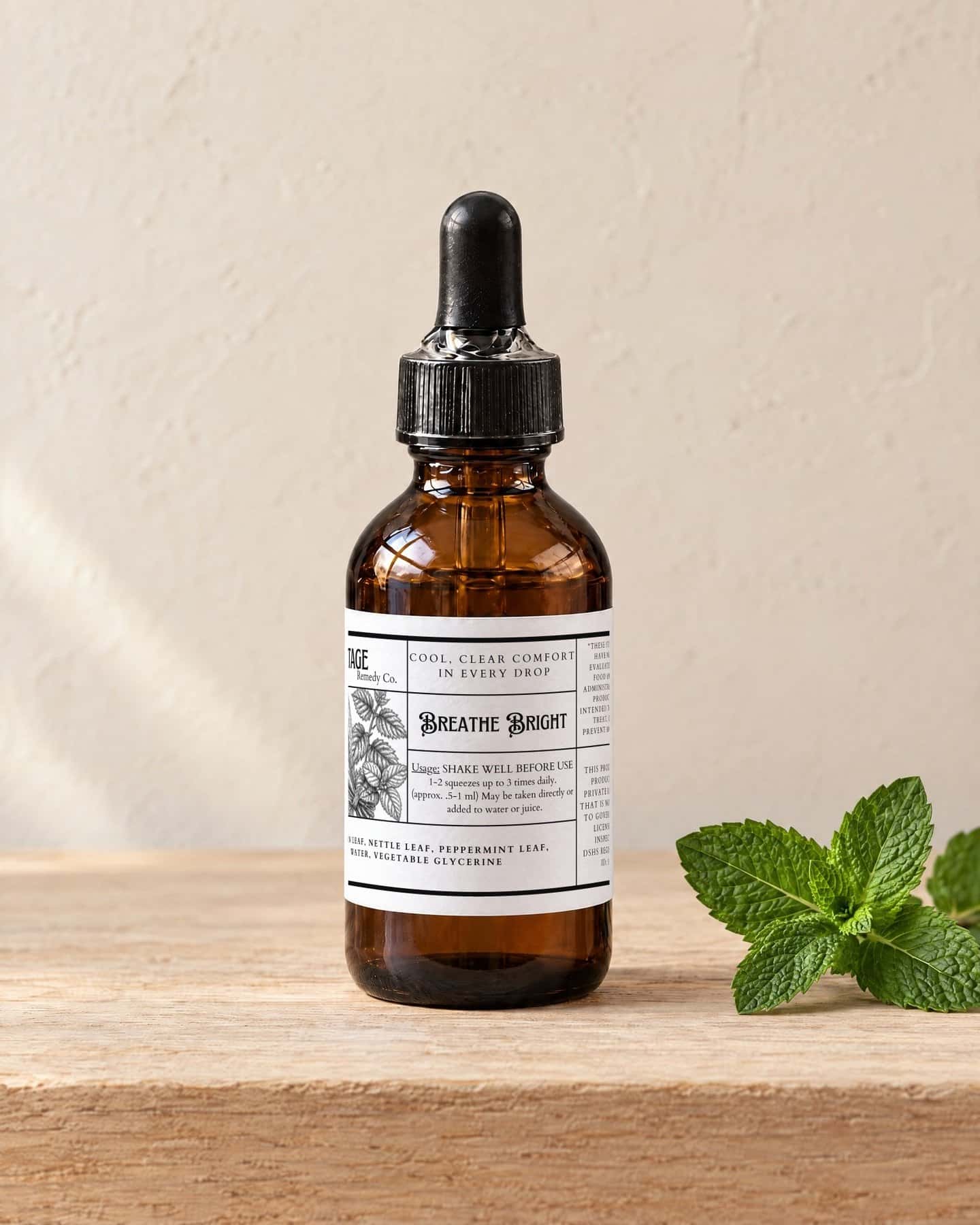 A dropper bottle of Breathe Bright Glycerite on a pale oak shelf, a sprig of fresh peppermint beside it