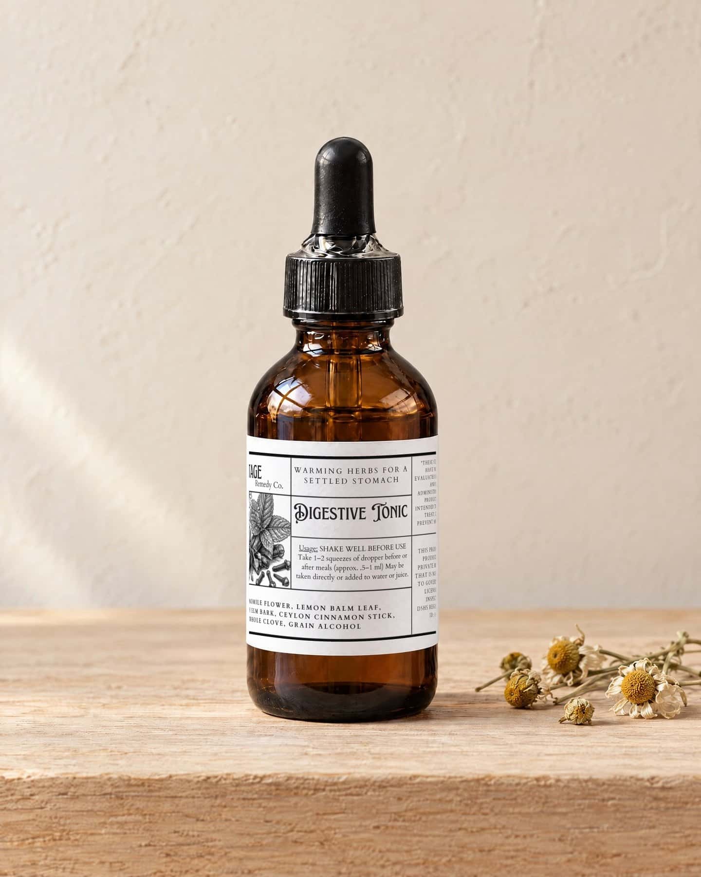A dropper bottle of Digestive Tonic on a pale oak shelf, a few dried chamomile flowers beside it