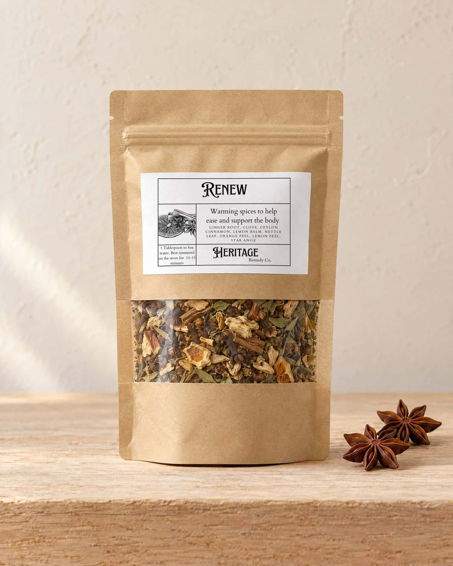 A kraft pouch of Renew - Inflammation Support Tea with a window onto the loose tea, on a pale oak shelf, two star anise pods beside it